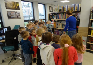 Dzieci stoją przed regałami z książkami.